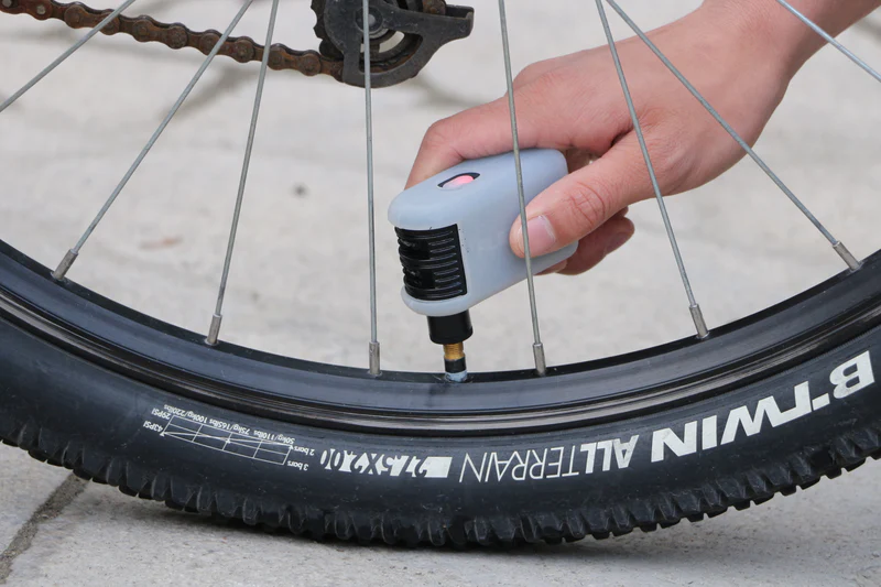 A person inflating a tyre with an electric bike pump