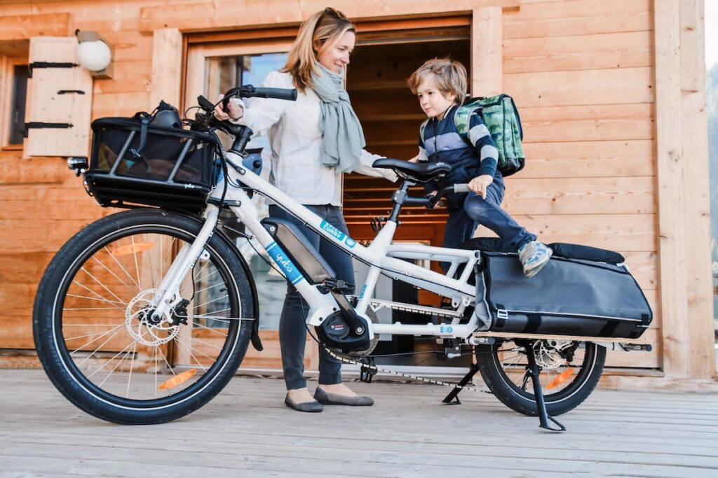 A mother making his kid sit in a cargo bike to go school