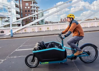 A person driving a cargo electric bike on street with items inside the front rack