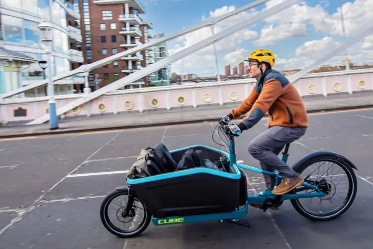 A person driving a cargo electric bike on street with items inside the front rack