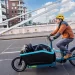 A person driving a cargo electric bike on street with items inside the front rack