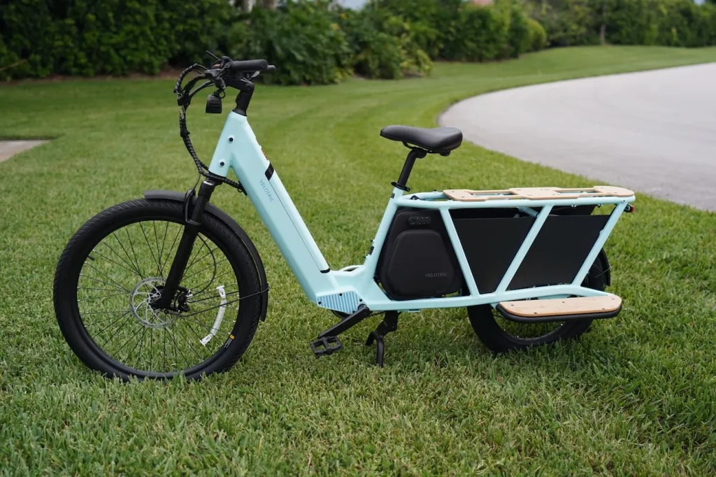 A view of a light blue Velotric Parker Electric Cargo Bike in grass