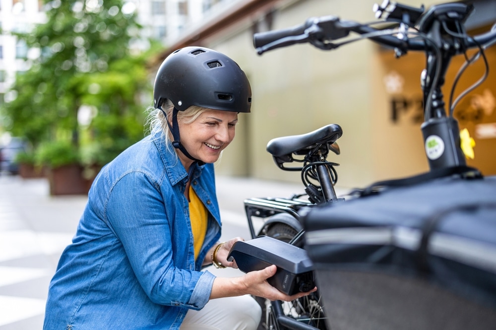 A view of an old lady inserting a battery into an e bike