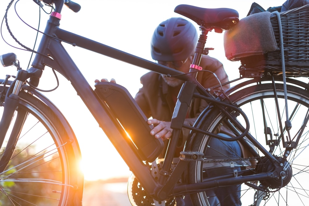 A view of an old man fixing battery into e bike