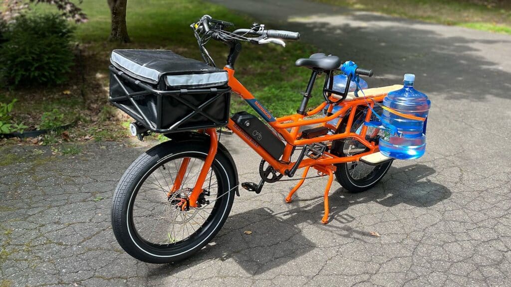 A view of an orange Rad Power RadWagon Bike carrying water cans