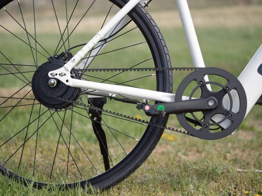 A view of bike rear wheel with a belt drive chain in grass