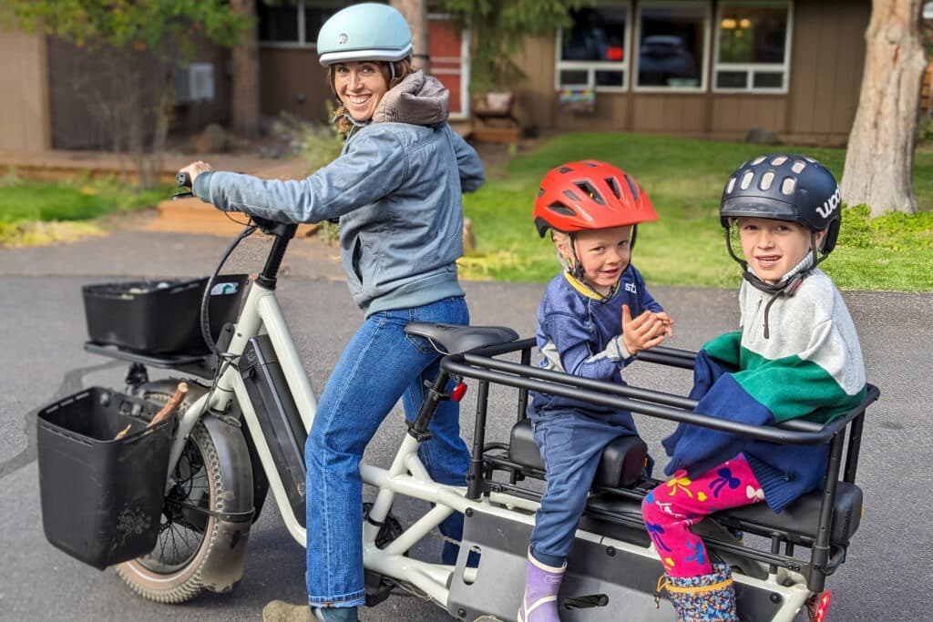 A view of children sitting inside a cargo bike inside the rear rack