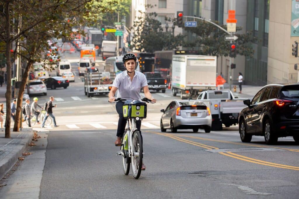 A girl riding an e bike on the road in between traffic