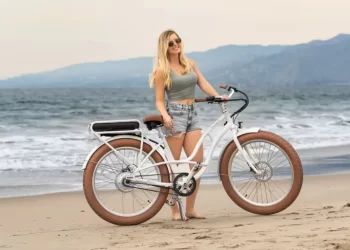 A girl standing with an e bike on a beach