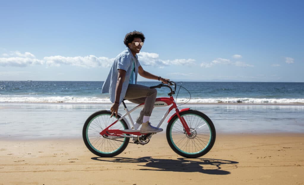 A guy comfortably sitting on an electric bike on a beach sand