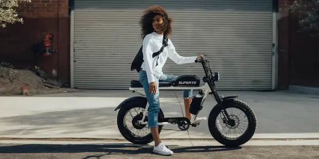 A view of a girl sitting on an electric bike outside a garage