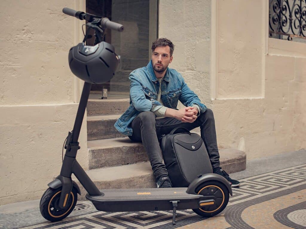 a man sitting on stairs with his segway ninebot scooter standing in front