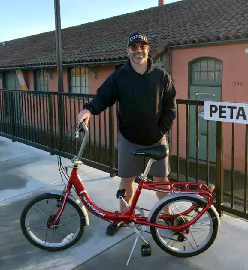 a man standing by holding his Schwinn Loop bike