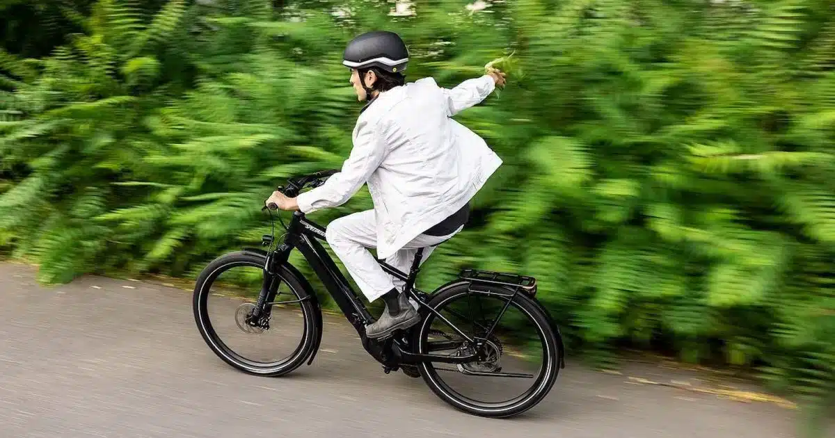 A backview of a guy riding a class e bike speedily by the trees