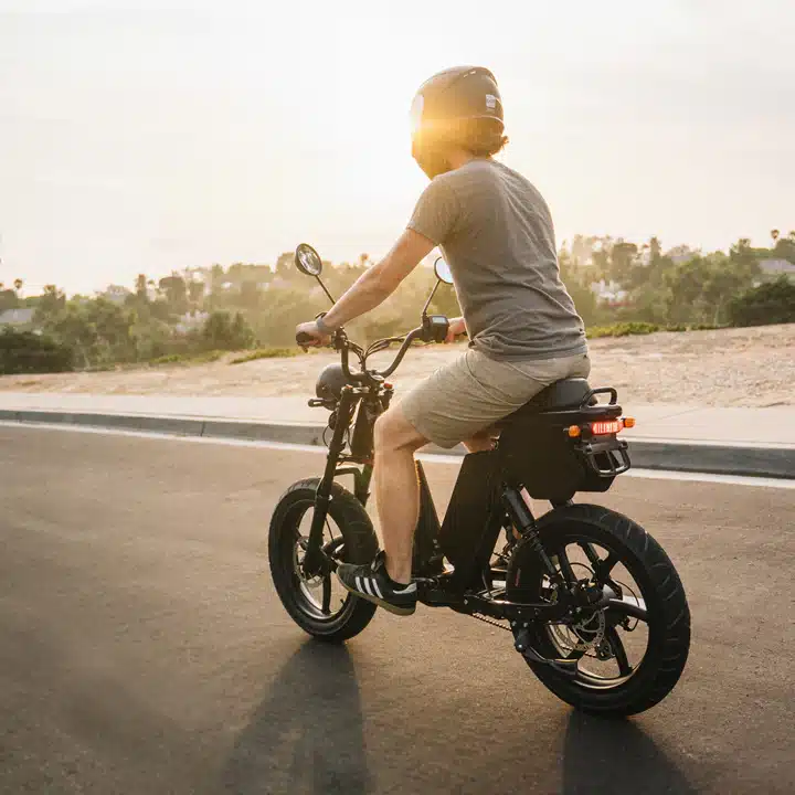 A backview of a person riding an e bike on road with sun light ahead