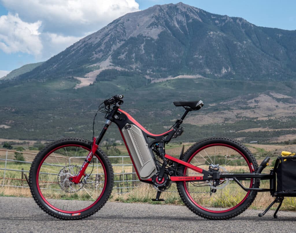 A side view of a the everest edition long range electric optibike r standing on a road by a mountain side