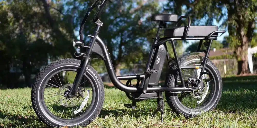 A view of a black two person bike parked in grass