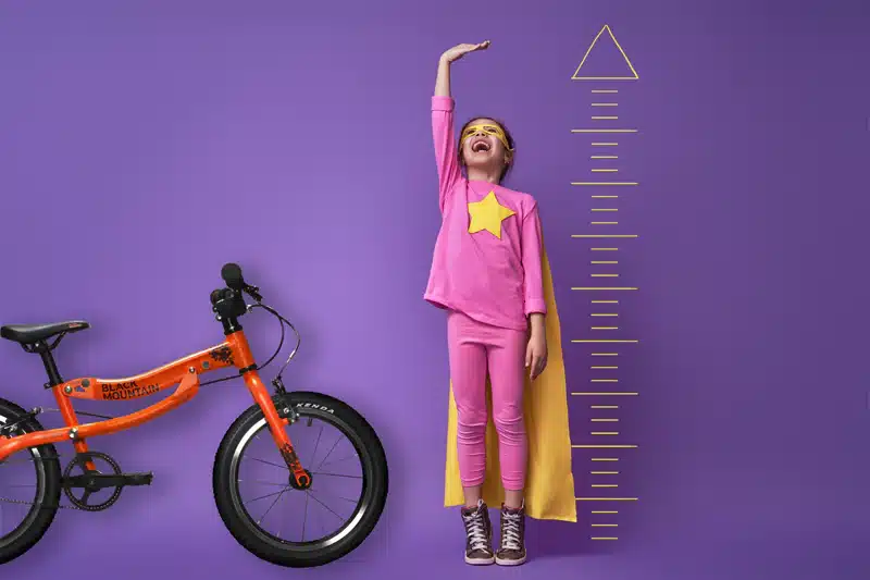 A view of a girl measuring her height alongside a bike with a height chart