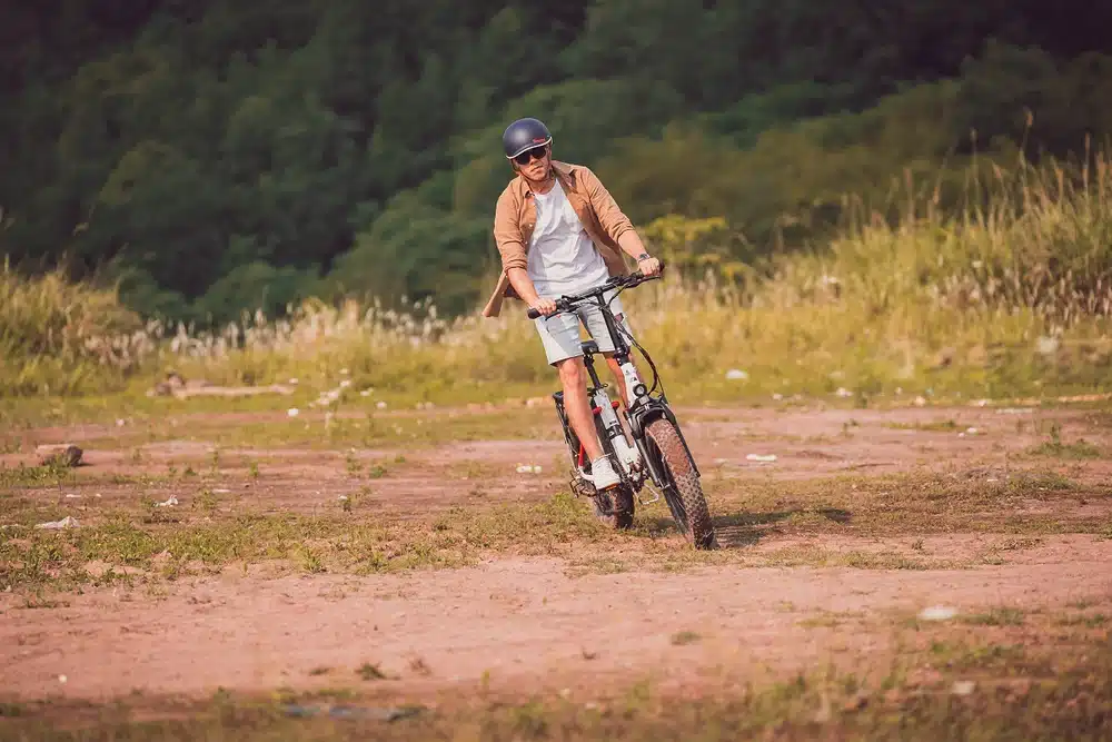 A view of a guy riding a bike in a grassy field