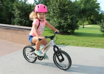 A view of a happy girl in pink riding a bicycle