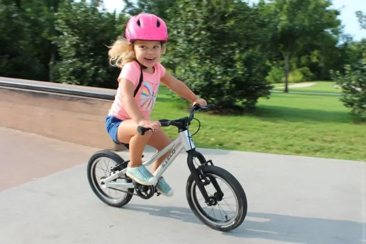 A view of a happy girl in pink riding a bicycle