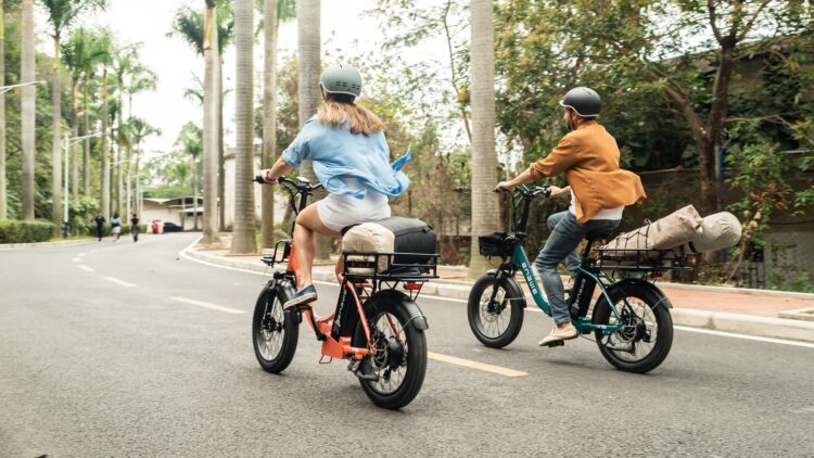 A back view of two people riding e bikes on road