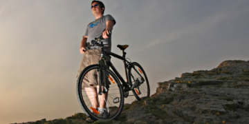 A view of a guy standing at a mountian with a hybrid bike