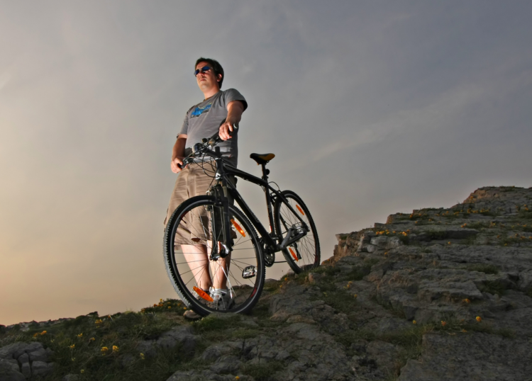 A view of a guy standing at a mountian with a hybrid bike