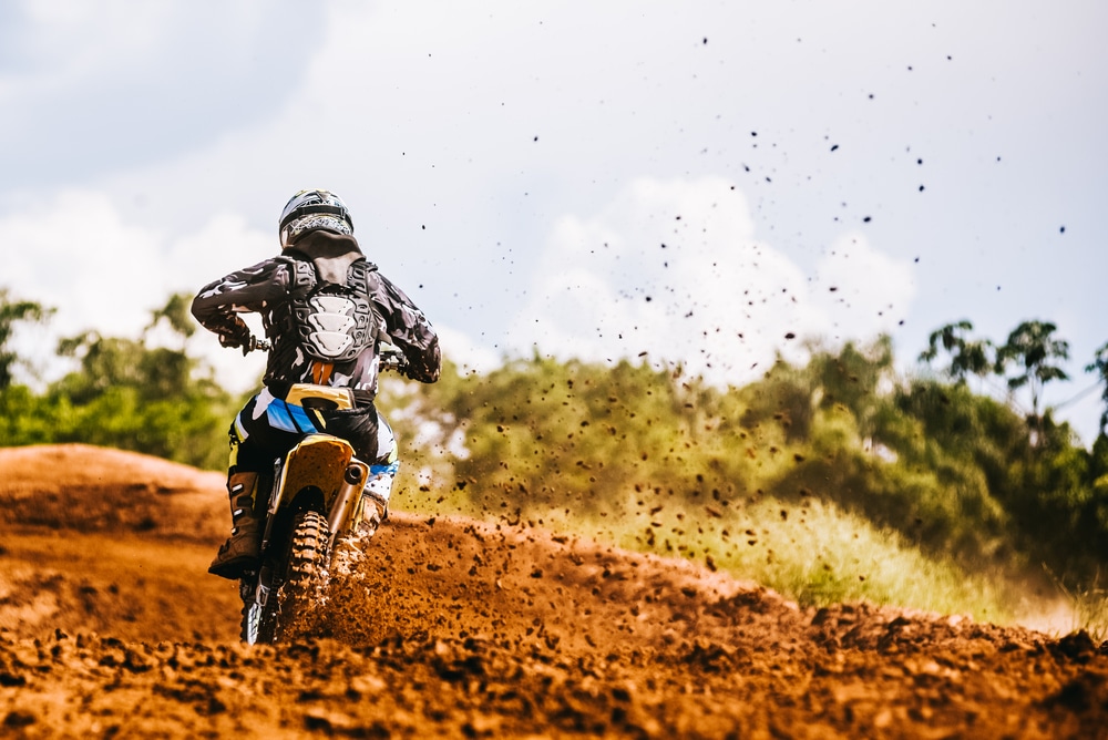 A back view of a person riding a dirt bike on road