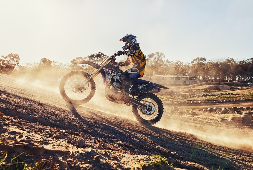 A view of a person riding a dirt bike uphill in mud