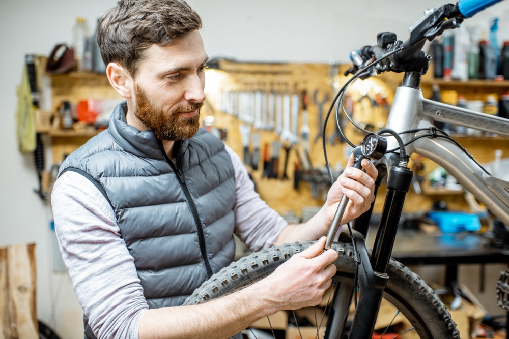 A view of a guy checking the shock suspension of the mountain bike