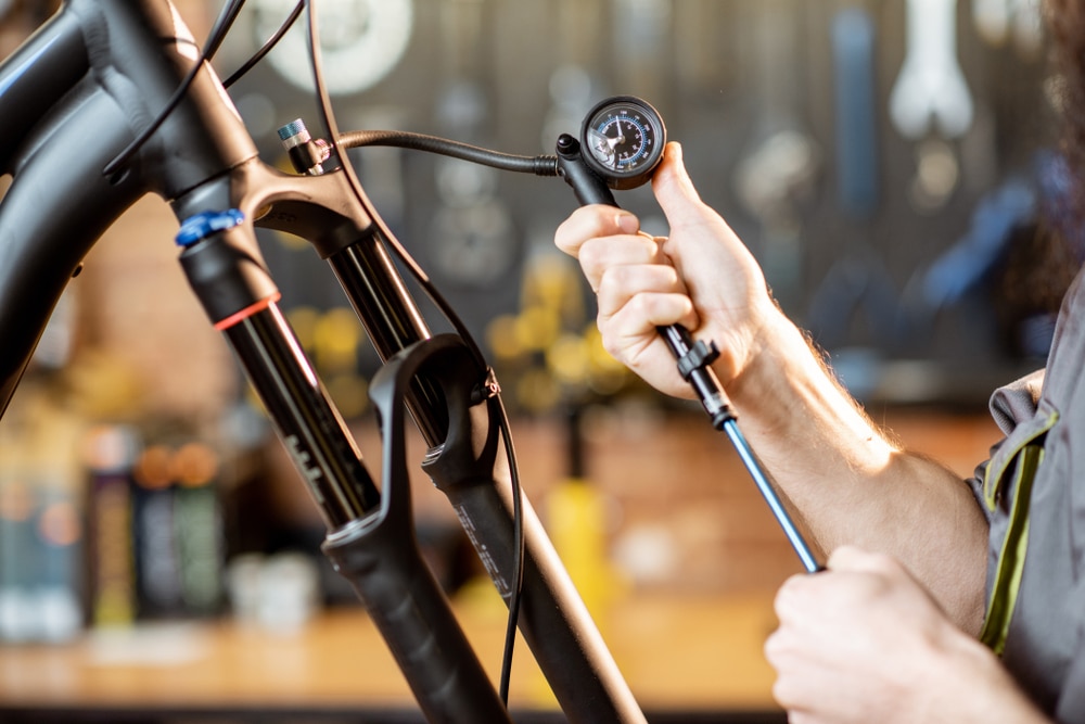 A view of a person using a shock pump on a mountain bike