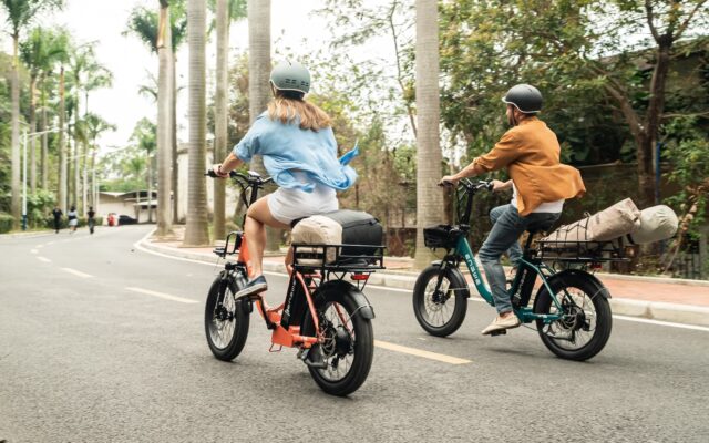 A back view of two people riding e bikes on road