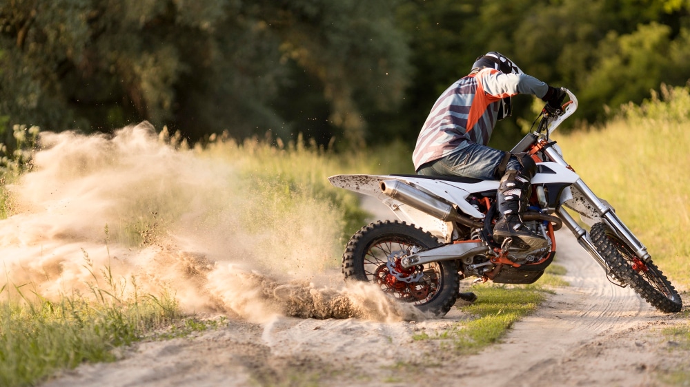 A backview of a person riding a pit bike in forest A backview of a person riding a pit bike in forest