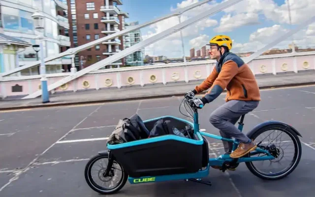 A person driving a cargo electric bike on street with items inside the front rack