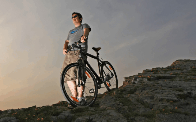A view of a guy standing at a mountian with a hybrid bike