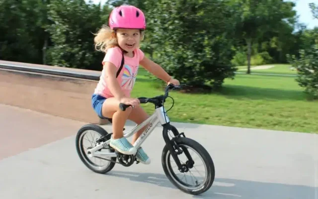 A view of a happy girl in pink riding a bicycle