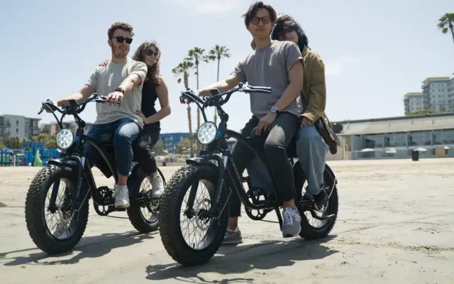 A view of two pair of people riding two seater electric bike